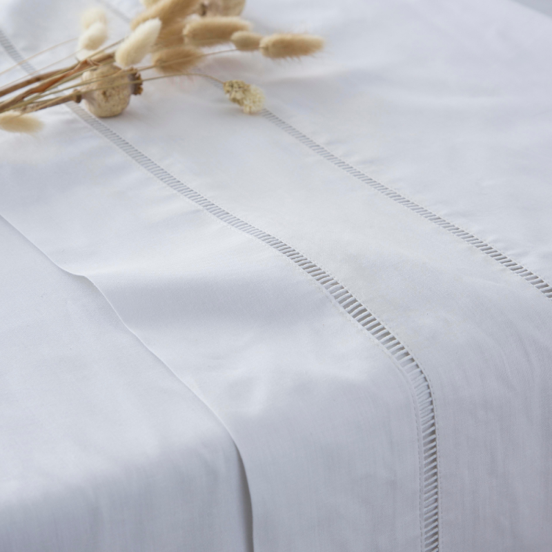 Sábanas de algodon para cama 150 Juego de sabanas en blanco decorado con cojines y mantas, acompañado de jarrones dorados.