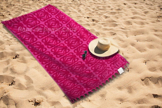 Toalla rosa en la arena con un sombrero y gafas de sol.