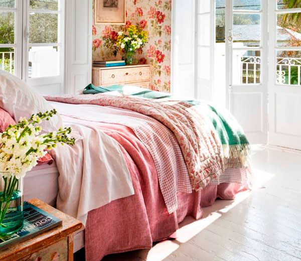 Rosa Habitación luminosa con cama cubierta de mantas suaves y decoración floral.