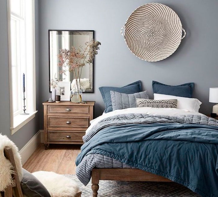 Azul Habitación acogedora con cama de tonos azules, mesa de noche de madera y espejo.