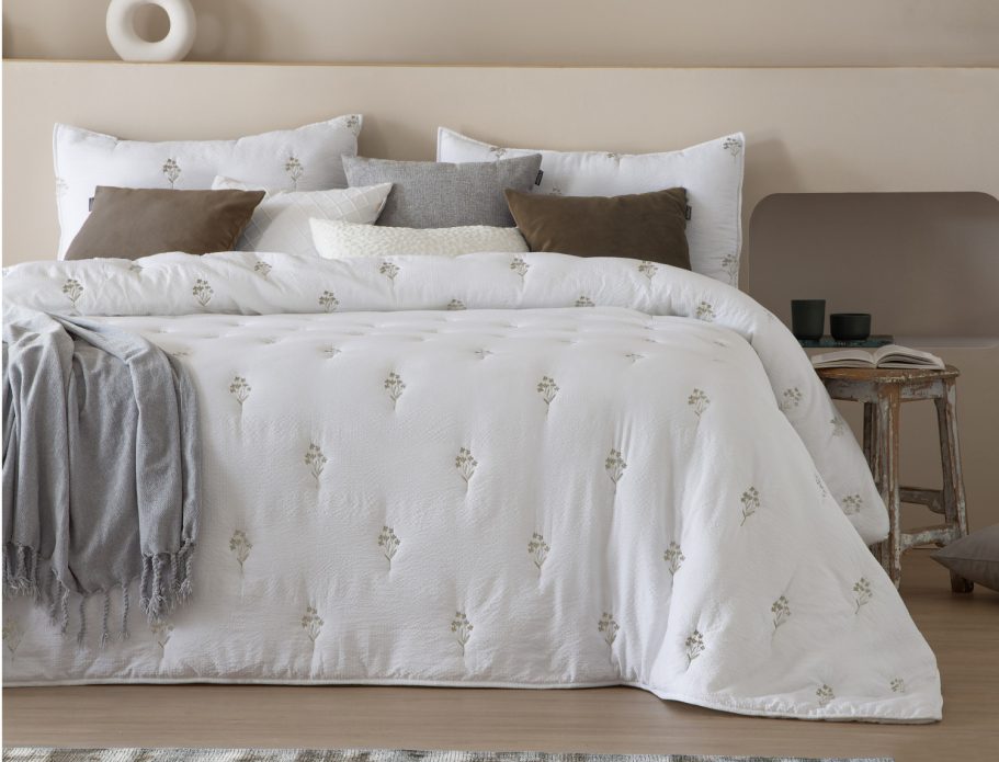 Conjunto de cama blanco con cojines y manta gris en un entorno elegante y acogedor.