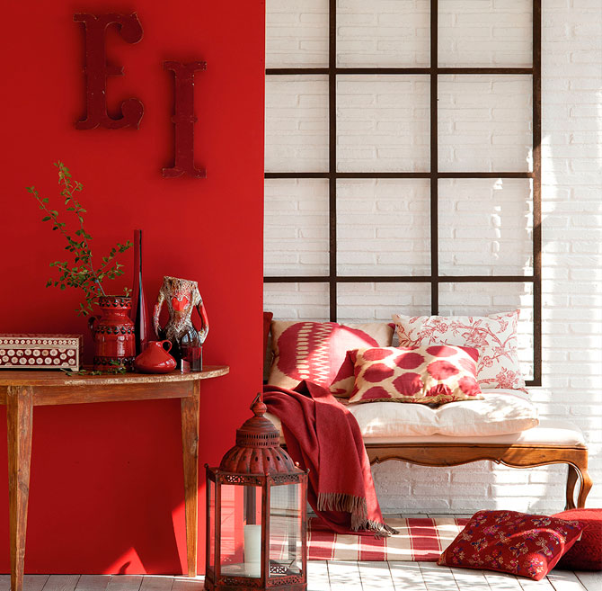 Rojo Habitación acogedora con paredes rojas, cama decorada y una mesa de madera.