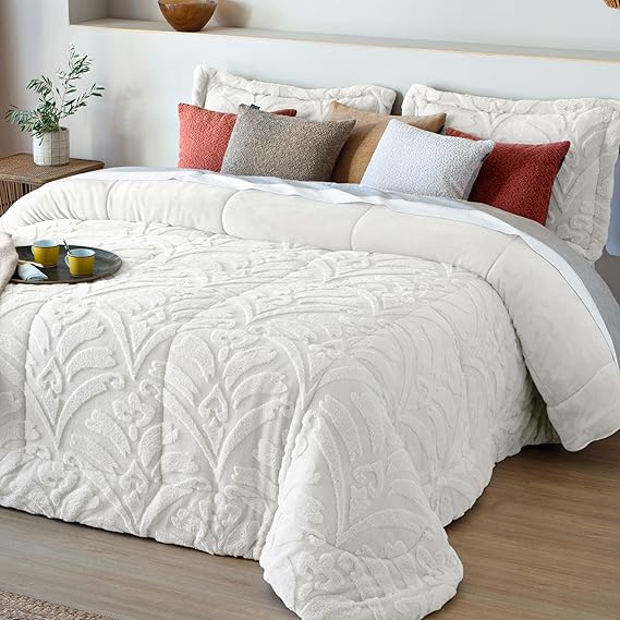 Edredón blanco con diseño de hojas, almohadas en tonos cálidos sobre una cama moderna.