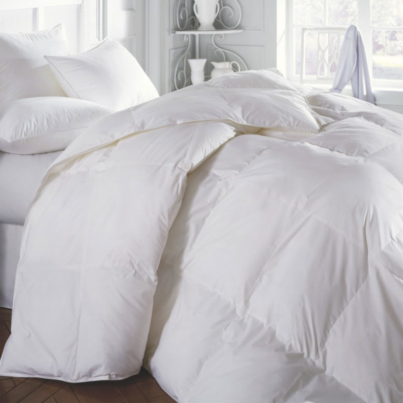 Edredón blanco y almohadas sobre una cama con sábanas suaves.