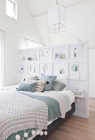 Cama con ropa de cama en tonos verdes y decoraciones minimalistas en un dormitorio luminoso.