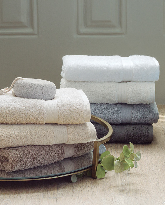 Toallas de diferentes colores apiladas en una bandeja junto a una barra de jabón.