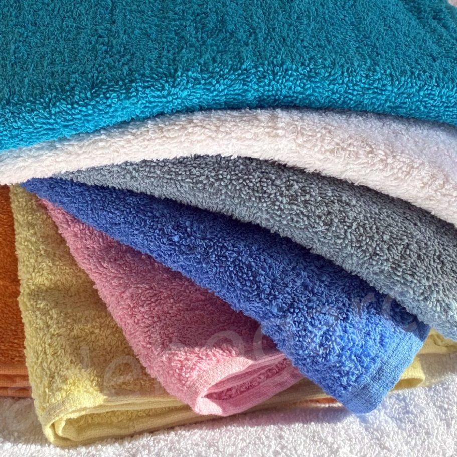 Toallas sueltas Toallas de diferentes colores apiladas, incluyendo azul, rosa y amarillo.