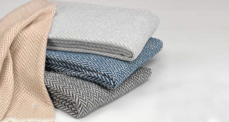 Multiusos Pilas de mantas de diferentes colores en tonos neutros y azul.