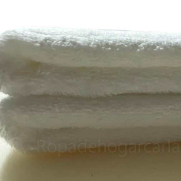 Toallas sueltas Toallas de diferentes colores apiladas: amarillo, naranja, azul, gris, rosa y blanco.